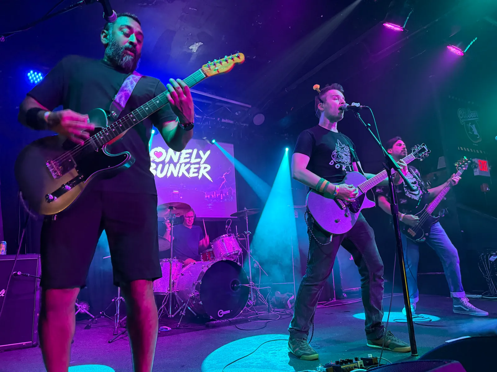 Lonely Bunker playing live at the Ottobar in Baltimore — all four members on stage, keyart projected behind the drum kit